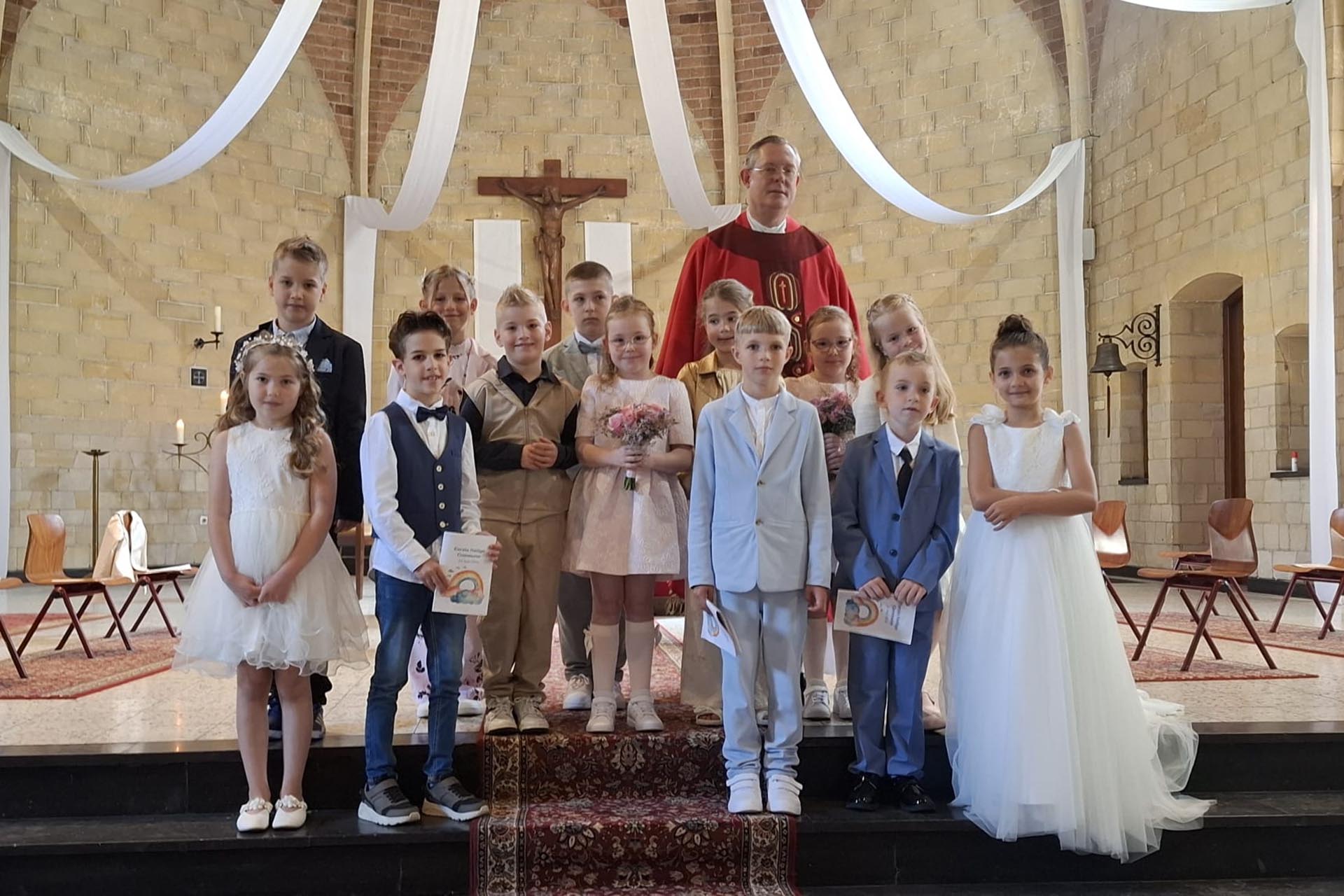 De communicantjes van Leuken, Graswinkel en Keent samen met pastoor Ivo Krewinkel