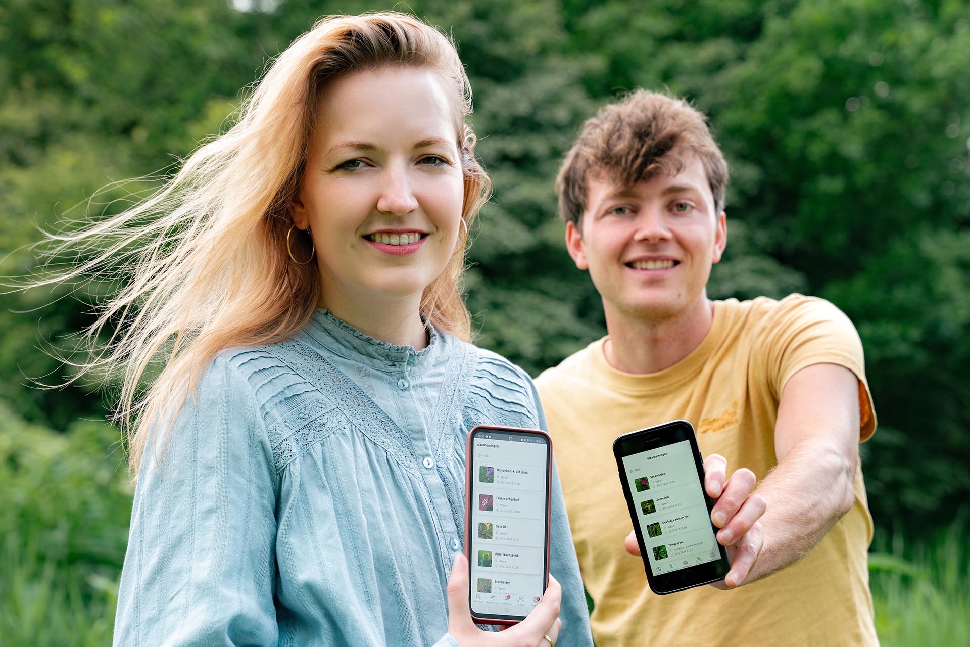 Twee mensen laten de natuurwaarnemingen app ObsIdentify op hun telefoon zien. Ingestuurde foto.