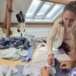 Twee deelnemers werken aan het wandkleed